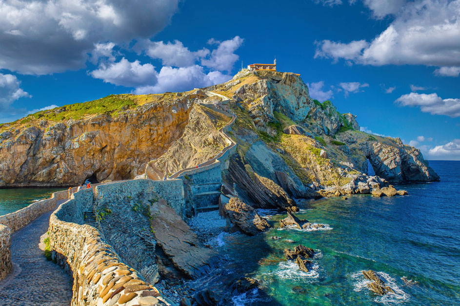 Vista de San Juan de Gaztelugatxe, en Vizcaya, con el camino de acceso serpenteando por la isla rocosa hasta la ermita, rodeada por el mar Cantábrico.