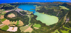 Vista aérea de Sete Cidades, en São Miguel, con sus lagos de aguas verdes y azules rodeados de bosques, campos agrícolas y cráteres volcánicos.