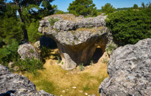 Formaciones rocosas calizas de los Callejones de Las Majadas, con arcos naturales y vegetación de pinos y arbustos en la Serranía de Cuenca.