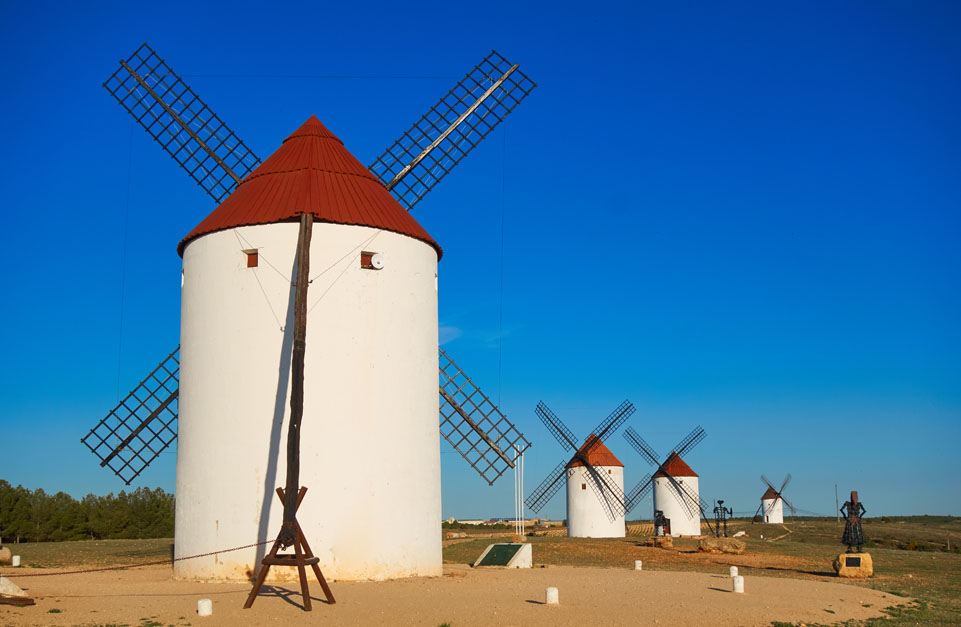 Molinos de viento tradicionales de Mota del Cuervo, en La Mancha, bajo un cielo azul.